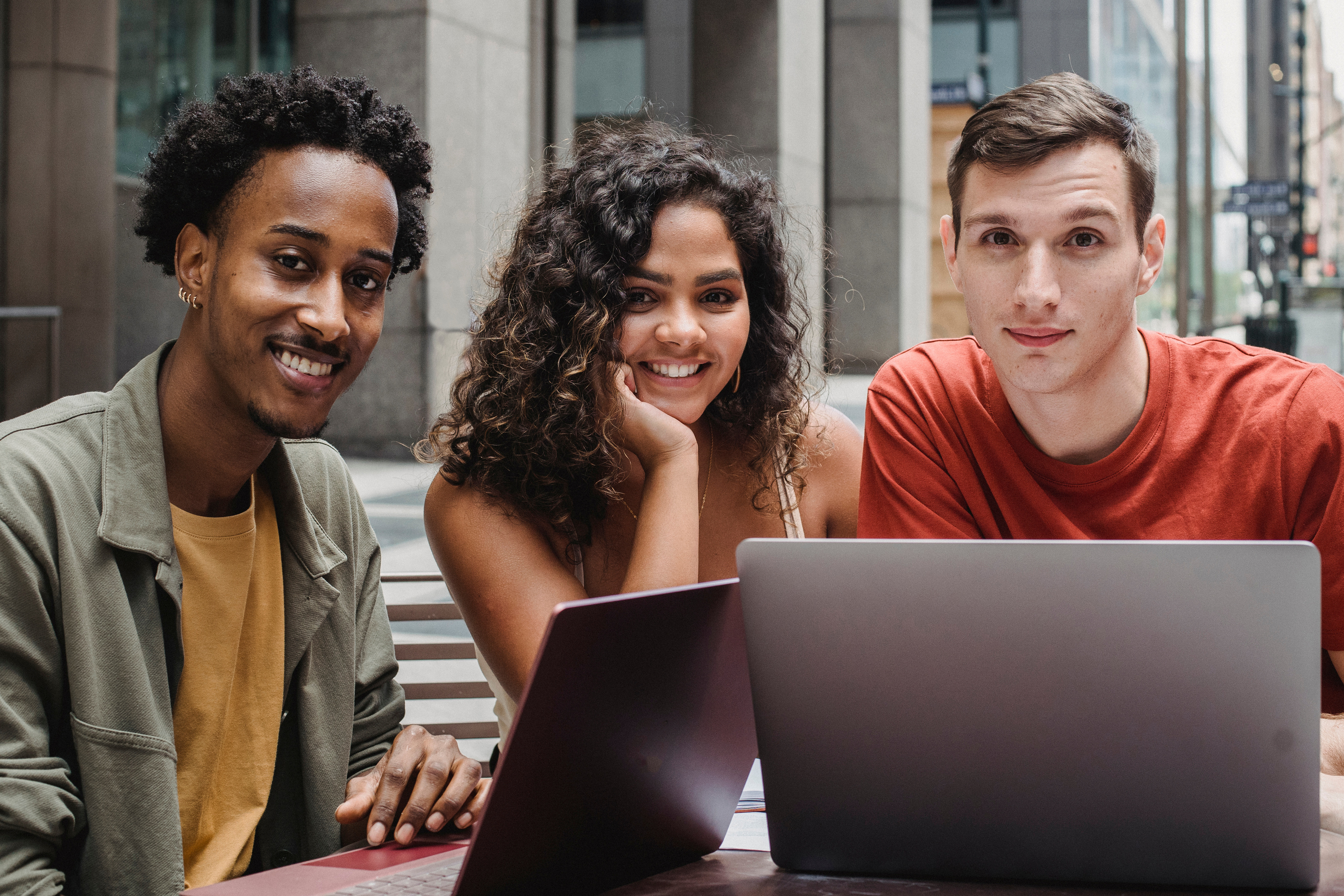 Multiracial students working on laptop in street